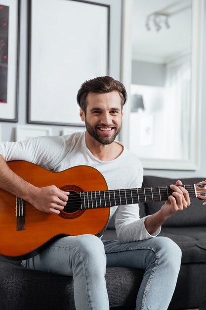 Gelukkige mensenzitting bij bank het spelen op gitaar