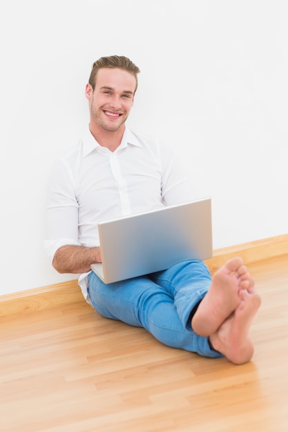 Gelukkige mensenzitting op de vloer die laptop met behulp van