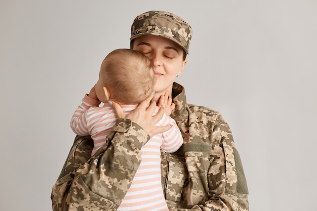 Gelukkige militaire moeder ontmoeting met dochtertje na missiereis, babymeisje in de armen houden en glimlachen, familiereünie of naar huis terugkeren.