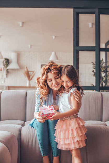 Gelukkige moeder die een cadeau uit de doos met dochtercadeaus neemt voor moederdag thuis