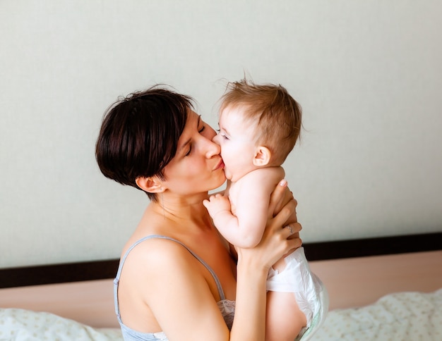 Gelukkige moeder die haar baby vasthoudt. moeder kust haar baby