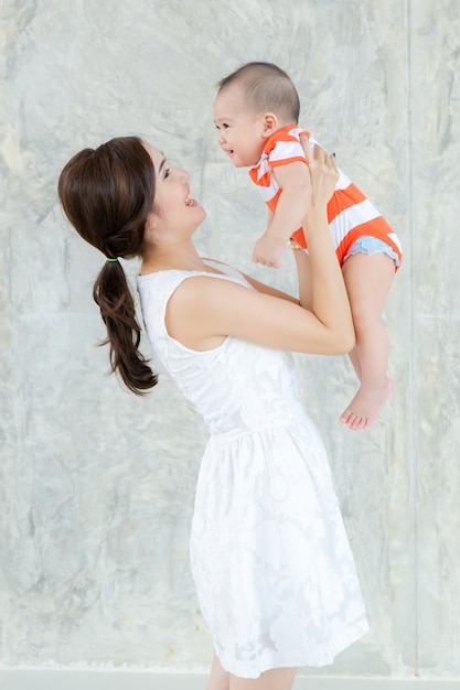 Gelukkige moeder die haar babyjongen thuis houdt. Jonge moeder met haar schattige dochtertje