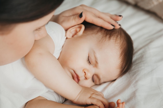 Gelukkige moeder die haar slapende baby kust