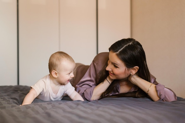 Gelukkige moeder die plezier heeft en lacht met haar baby op het bed