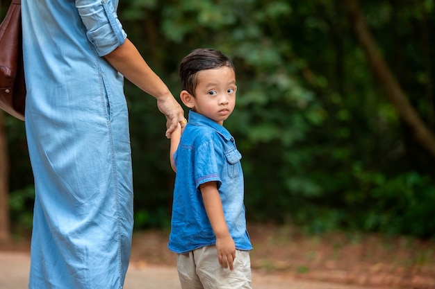 Foto gelukkige moeder en aanbiddelijke kleine jongen die van warm weer genieten bij mooi park