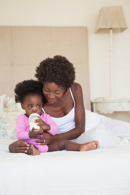 Gelukkige moeder en babymeisjeszitting op bed samen