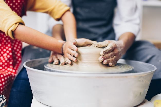 Gelukkige moeder en dochter die kleiaardewerk maken op een spinwiel.