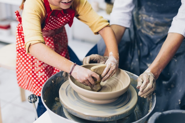 Gelukkige moeder en dochter die kleiaardewerk maken op een spinwiel.