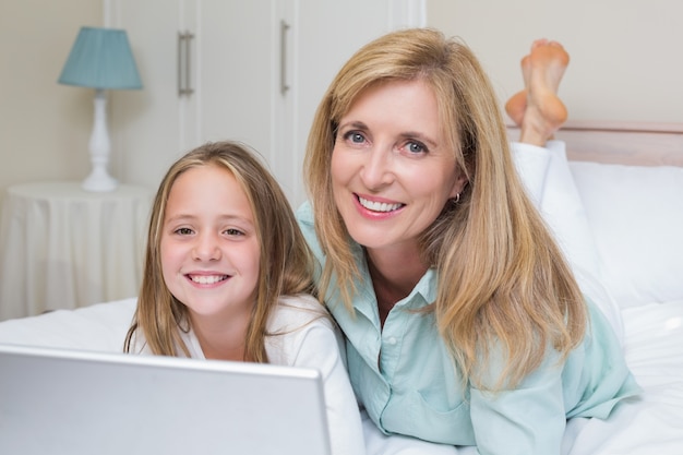 Gelukkige moeder en dochter die laptop met behulp van