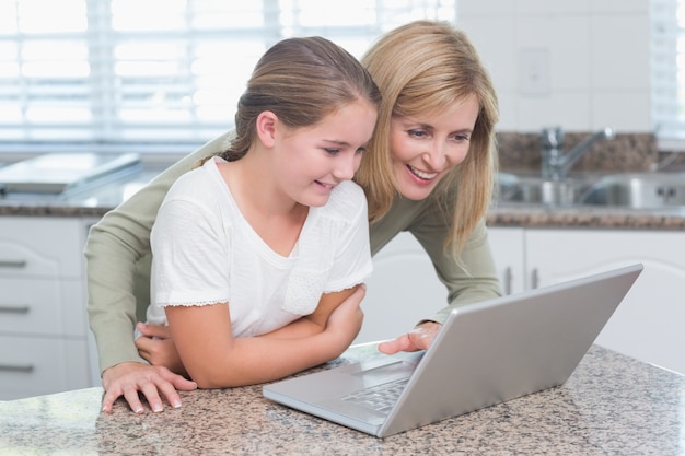 Gelukkige moeder en dochter die laptop samen met behulp van