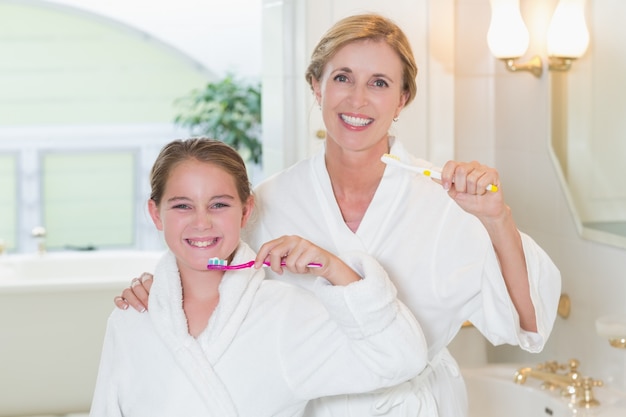 Gelukkige moeder en dochter die tanden samen borstelen
