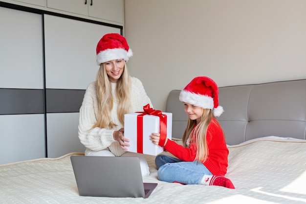 Foto gelukkige moeder en dochter die vrienden met videogesprek vieren. online kerstviering