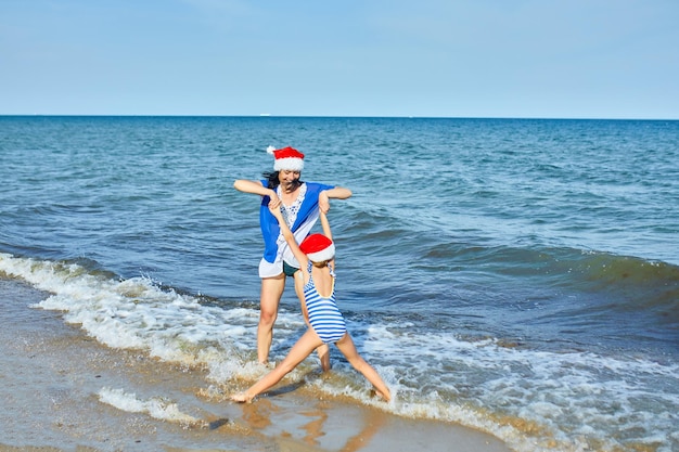 Gelukkige moeder en dochter in kerstmutsen die plezier hebben