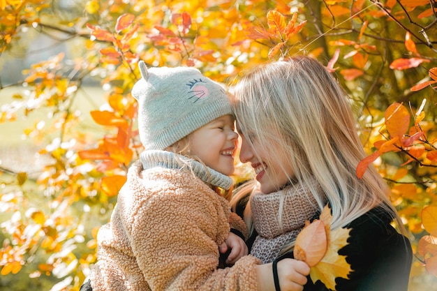 Gelukkige moeder en dochter lopen in het herfstpark Mooie familie in warme kleren Herfst