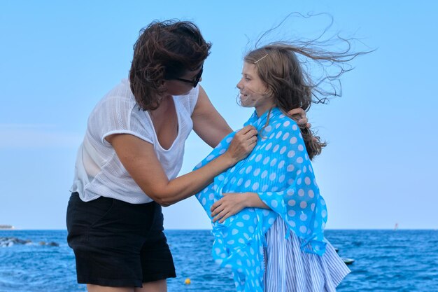 Gelukkige moeder en dochter lopen samen langs het zeestrand, moeder zorgt voor haar kind. Familieweekend, reizen, zomervakantie concept