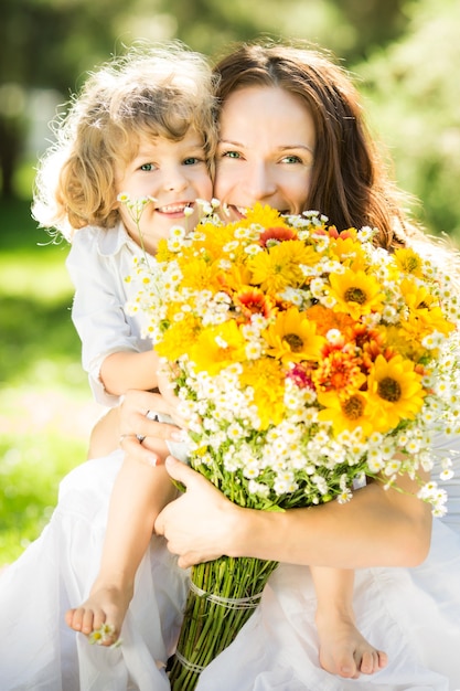 Gelukkige moeder en dochter met een groot boeket lentebloemen die buiten plezier hebben