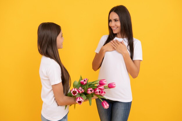 Gelukkige moeder en dochter met tulp bloemen op gele achtergrond bloemendag