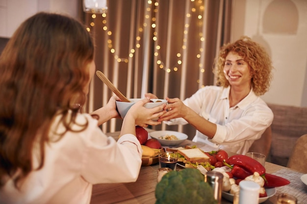 Gelukkige moeder en dochter staan 's avonds in de keuken