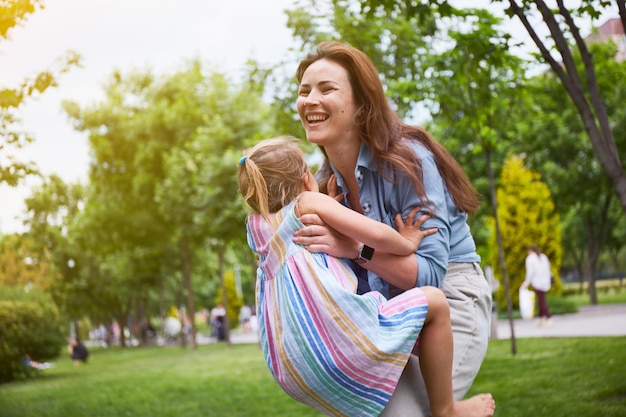 Gelukkige moeder en haar dochter spelen in het park. Genieten van de zomer. Gelukkig ouderschap