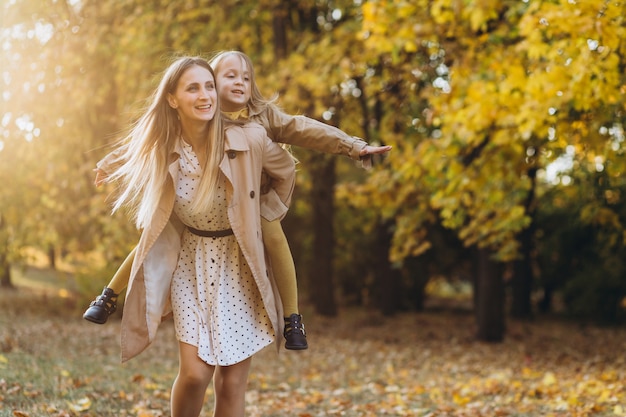 Gelukkige moeder en haar mooie dochter hebben plezier en wandelen in het herfstpark.