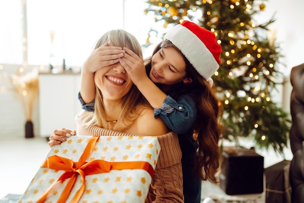 Gelukkige moeder en haar schattige dochtermeisje wisselen geschenken uit Vrolijk kerstfeest