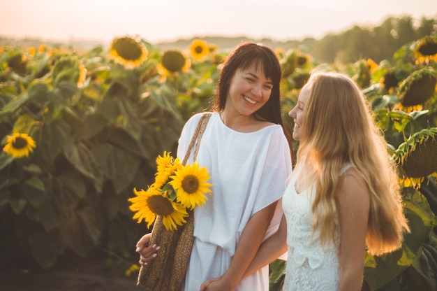 Gelukkige moeder en haar tienerdochter op het zonnebloemgebied