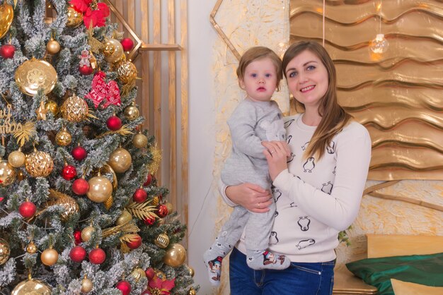 gelukkige moeder en klein kind in de buurt van de kerstboom in kerstmis