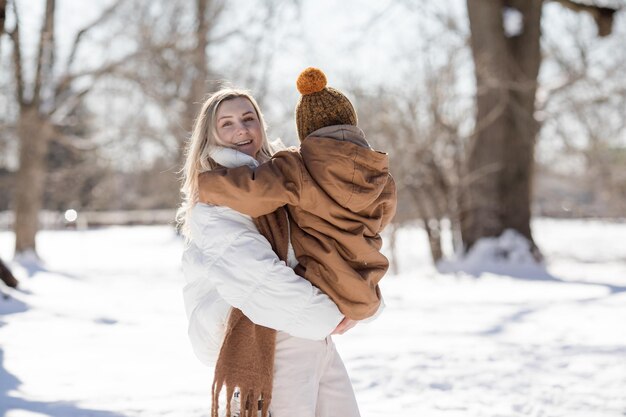 Gelukkige moeder en twee zonen die sneeuwballen spelen op een besneeuwde straat in de voorstad Gelukkige familie in het winterweekend Kerstvakanties