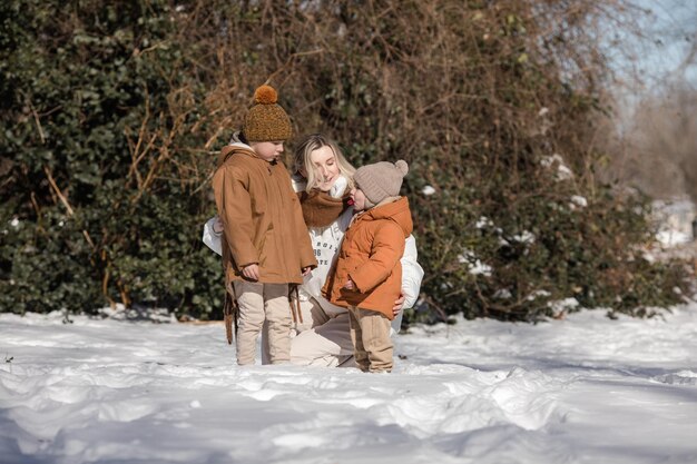 Gelukkige moeder en twee zonen die sneeuwballen spelen op een besneeuwde straat in de voorstad Gelukkige familie in het winterweekend Kerstvakanties