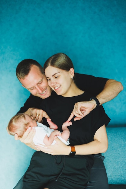 Foto gelukkige moeder en vader houden hun pasgeboren baby in hun armen jonge moeder en vader knuffelen een pasgeboren baby jonge familie en pasgeboren baby thuis