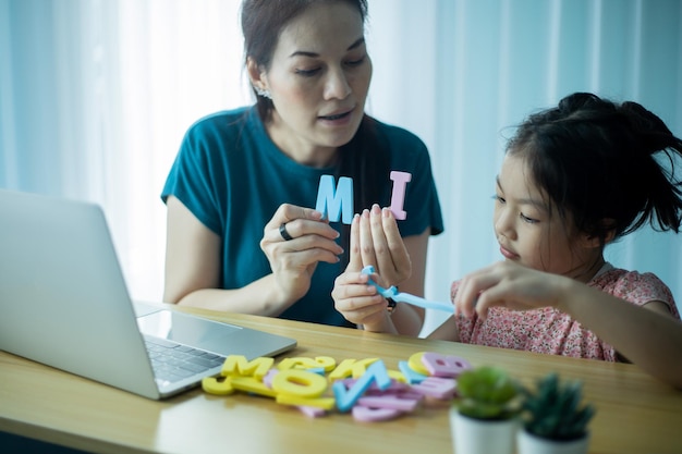 Gelukkige moeder en voorschoolse dochter spelen met een reeks kleurenletters