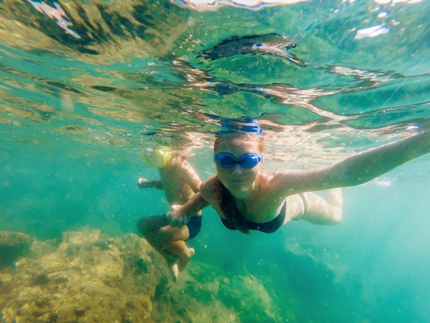 Gelukkige moeder en zoon die op strand snorkelen.