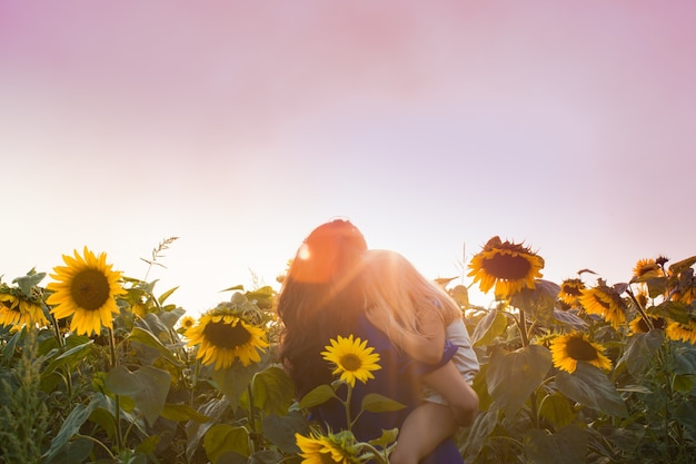 Gelukkige moeder knuffelt haar dochter in een zonnebloemveld