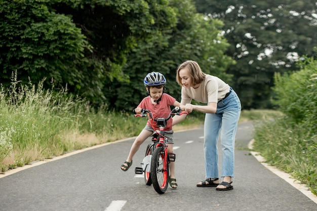 Gelukkige moeder leert zoontje fietsen op het fietspad