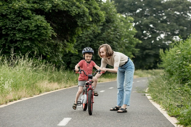 Gelukkige moeder leert zoontje fietsen op het fietspad