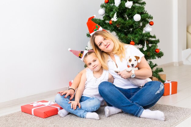 Gelukkige moeder met haar dochter en de hondzitting van Jack Russell Terrier dichtbij de kerstboom