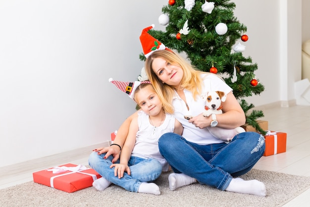 Gelukkige moeder met haar dochter en de hondzitting van Jack Russell Terrier dichtbij de kerstboom