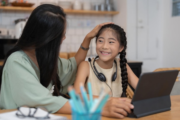 Gelukkige moeder met haar jonge dochter die geniet van online winkelen of thuiswerken Zaken op afstand en virtuele communicatie met familie en vrienden