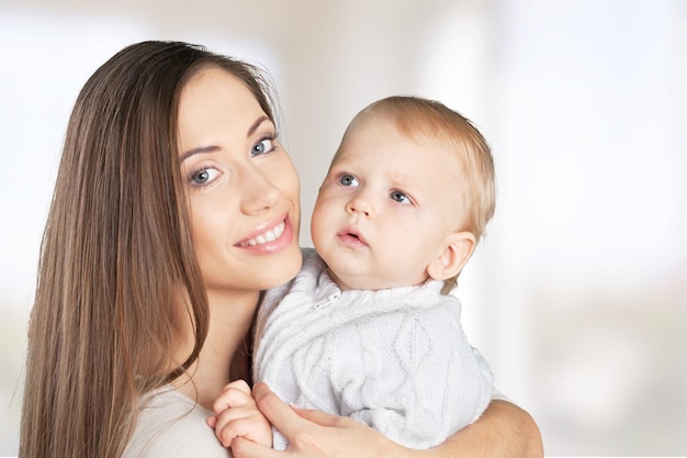 Gelukkige moeder met lieve babyjongen op achtergrond