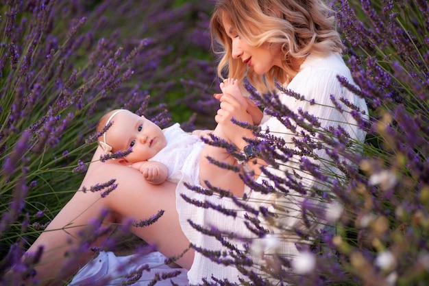 Gelukkige moeder met mooie dochter op lavendelachtergrond. Mooie vrouw en schattige baby