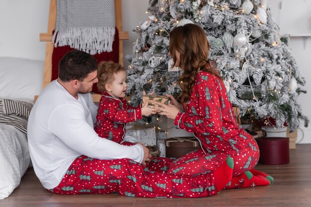 Gelukkige moeder, vader en dochter bij de kerstboom De ochtend voor kerst