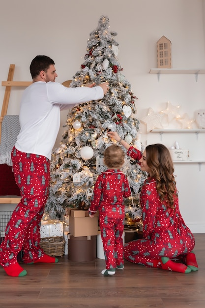 Gelukkige moeder, vader en dochter bij de kerstboom De ochtend voor kerst