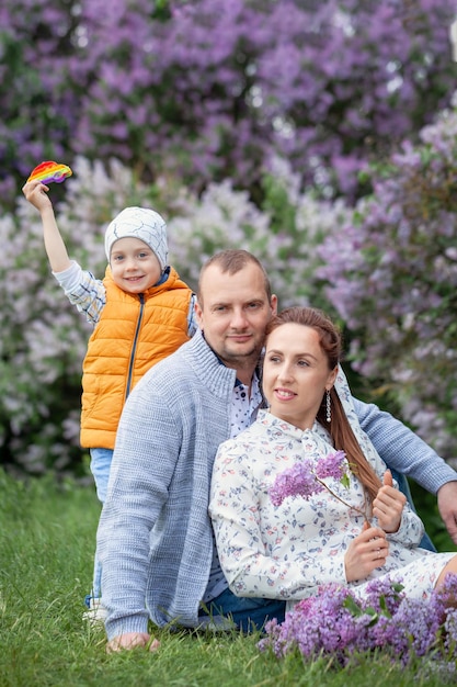 Gelukkige moeder, vader en zoontje met picknick in het zomerpark. Jonge ouders met jongen in groen park. Zoet moment familie samen concept.