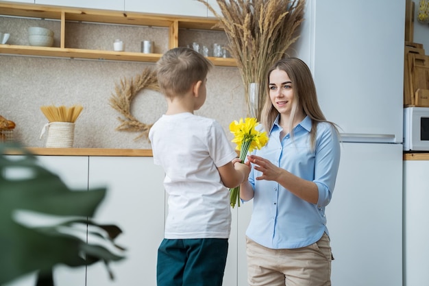 gelukkige moederdag zoontje geeft bloemen aan moeder jongen feliciteert moeder