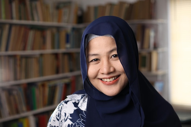 Gelukkige mooie Aziatische moslimvrouw met hijab die glimlacht naar de camera vrouwelijke student in de bibliotheek