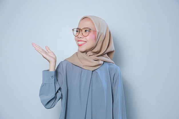 Gelukkige mooie jonge Aziatische moslimzakenvrouw die glazen draagt die aan leeg gebied richten