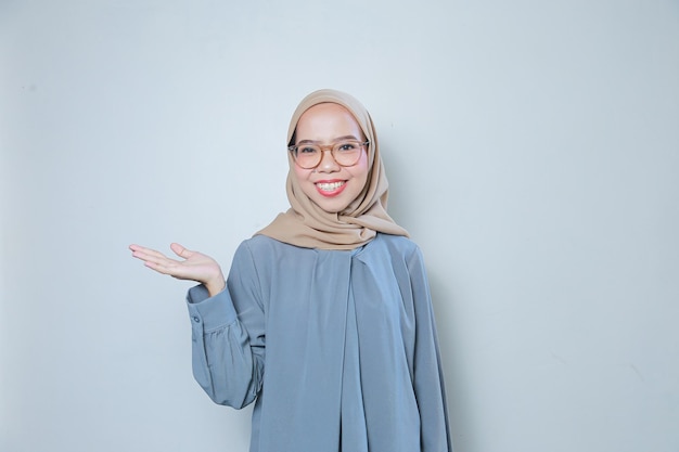 Gelukkige mooie jonge Aziatische moslimzakenvrouw die glazen draagt die aan leeg gebied richten