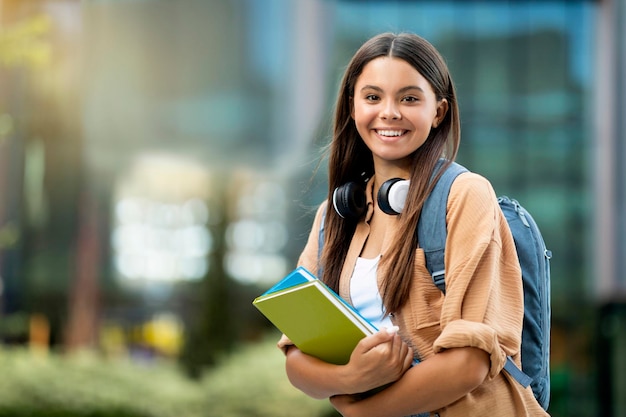 Gelukkige mooie jonge dame gaat naar de universiteit poseren op de campus