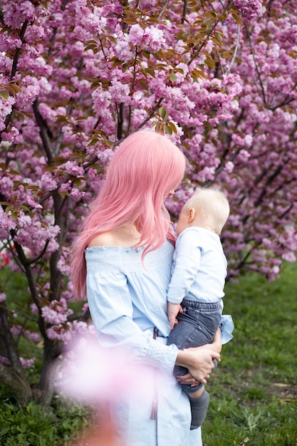 Gelukkige mooie jonge moeder met een kleine zoon in het park in de lente