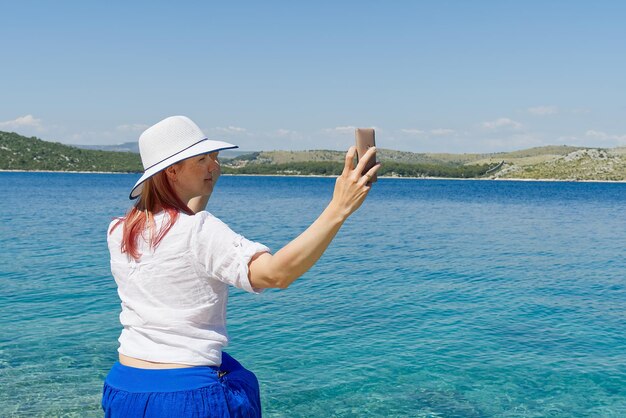 Gelukkige mooie jonge vrouw die geniet van vrijheid en de zomervakantie met uitzicht op zee